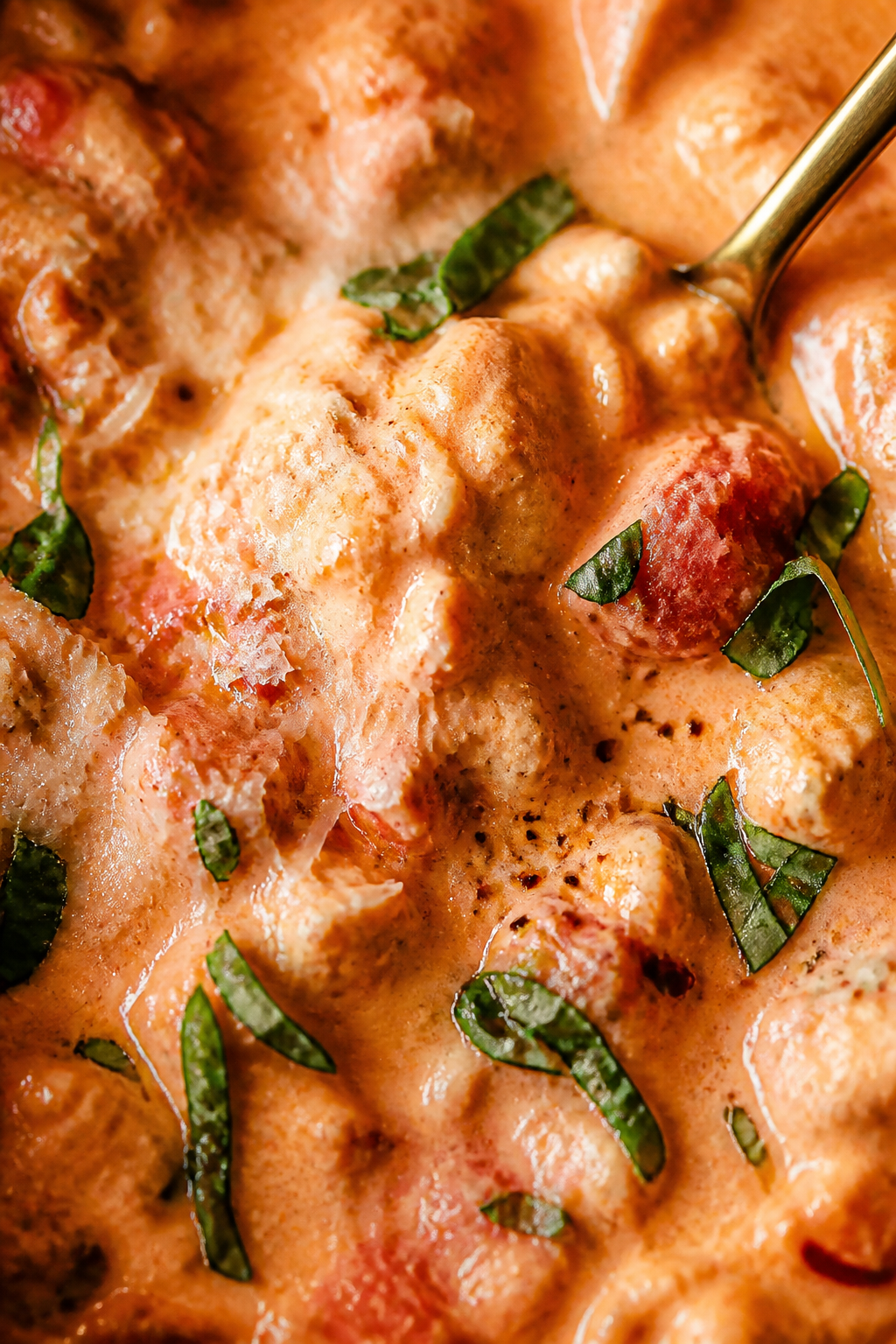 Close-up creamy finish: Ultra-close detail of the silky, blush-red creamy tomato basil sauce just af