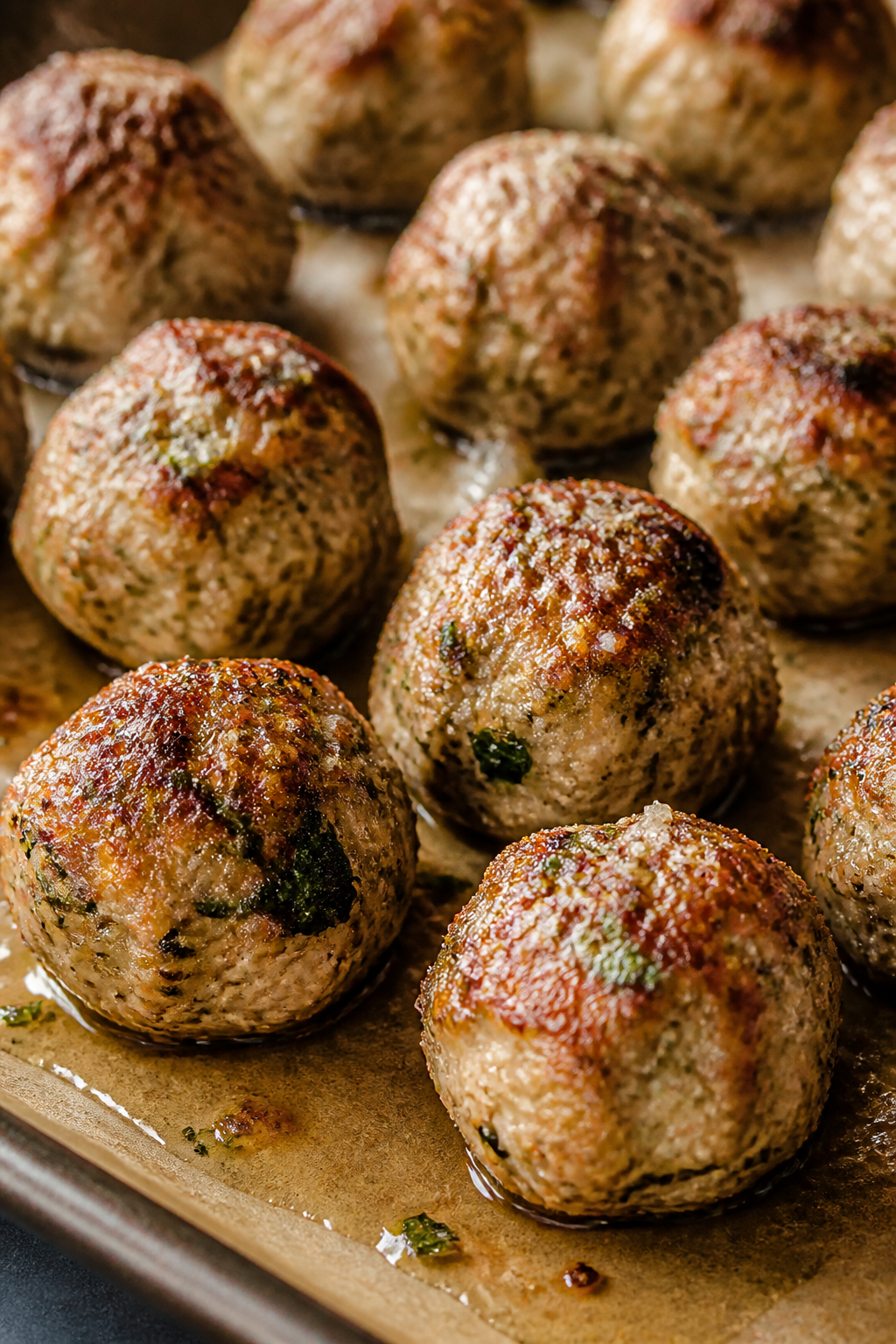 Close-up detail: Juicy baked turkey Italian herb meatballs just out of the oven on a parchment-lined