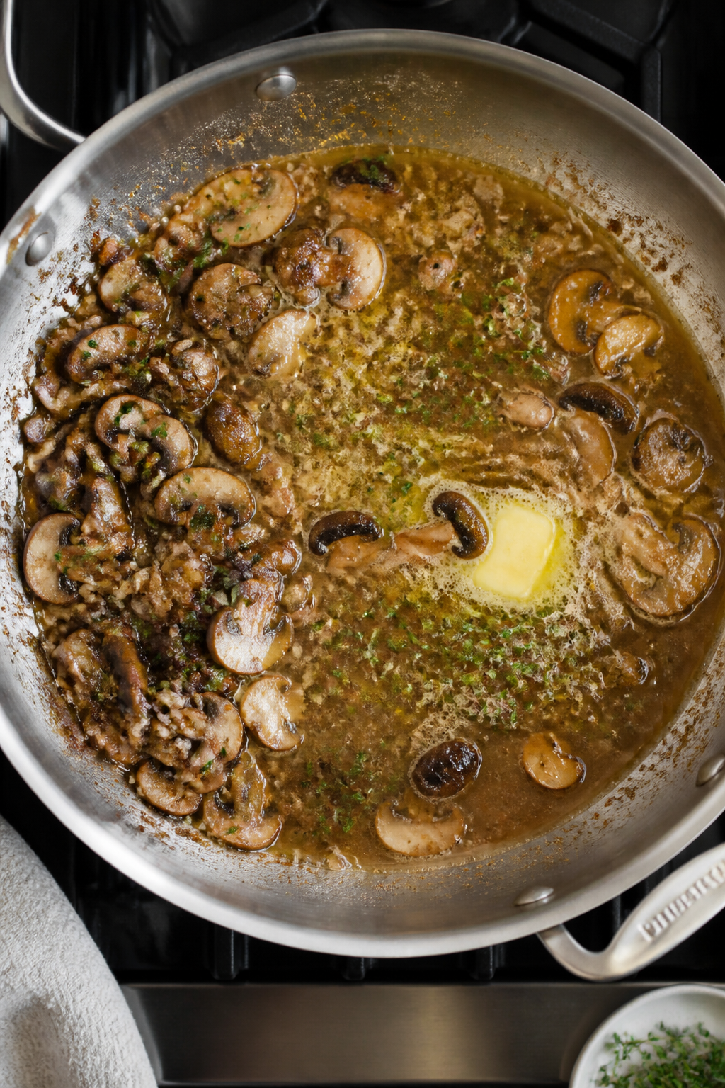 Cooking process: Overhead shot of the deglazing step—broth just poured into the hot skillet with s