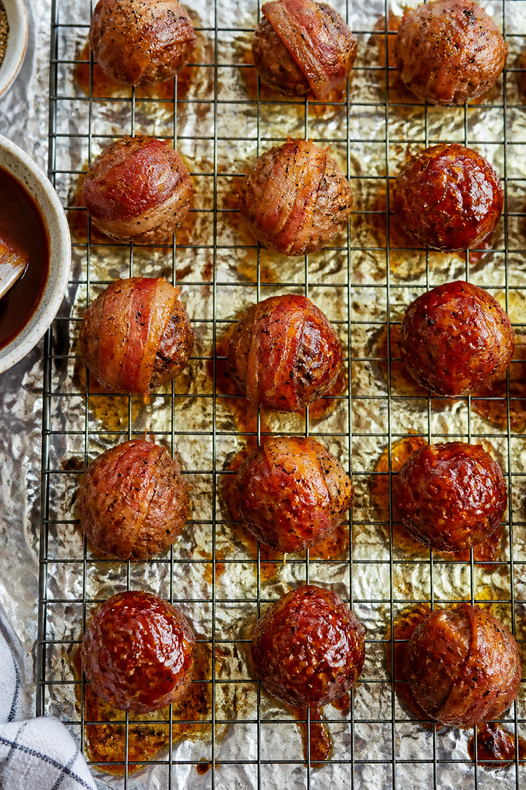 Tasty top view: Overhead shot of a sheet of evenly spaced bacon-wrapped meatballs on a wire rack mid