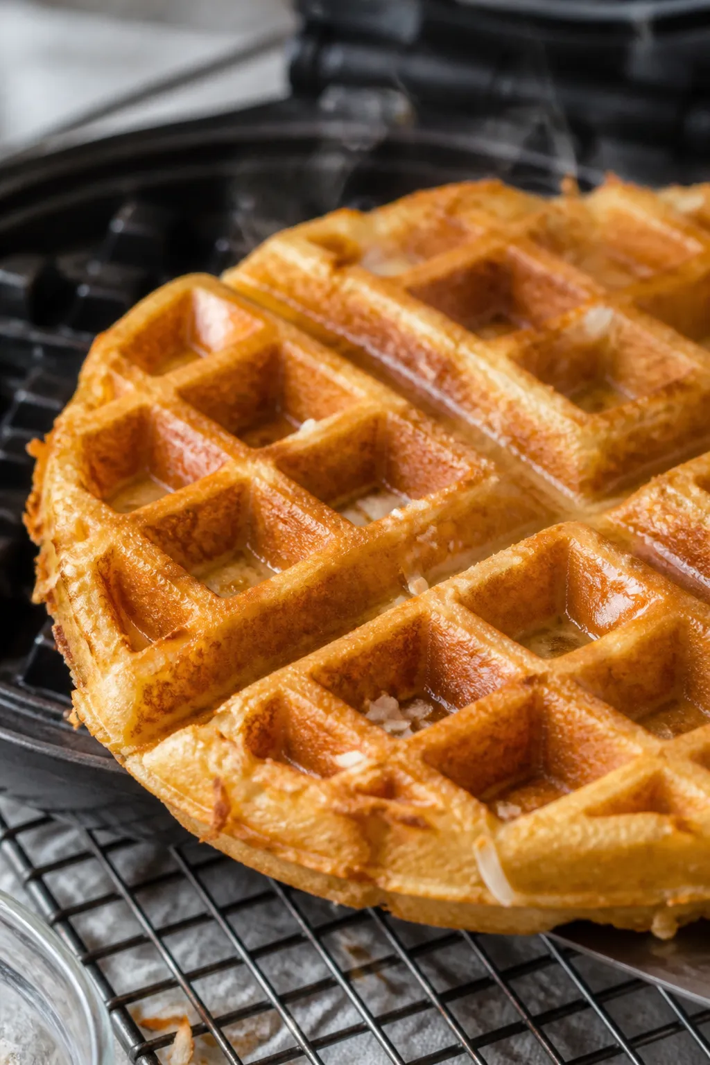 Close-up detail: A deep golden keto coconut flour waffle just lifted from a waffle iron, steam curli
