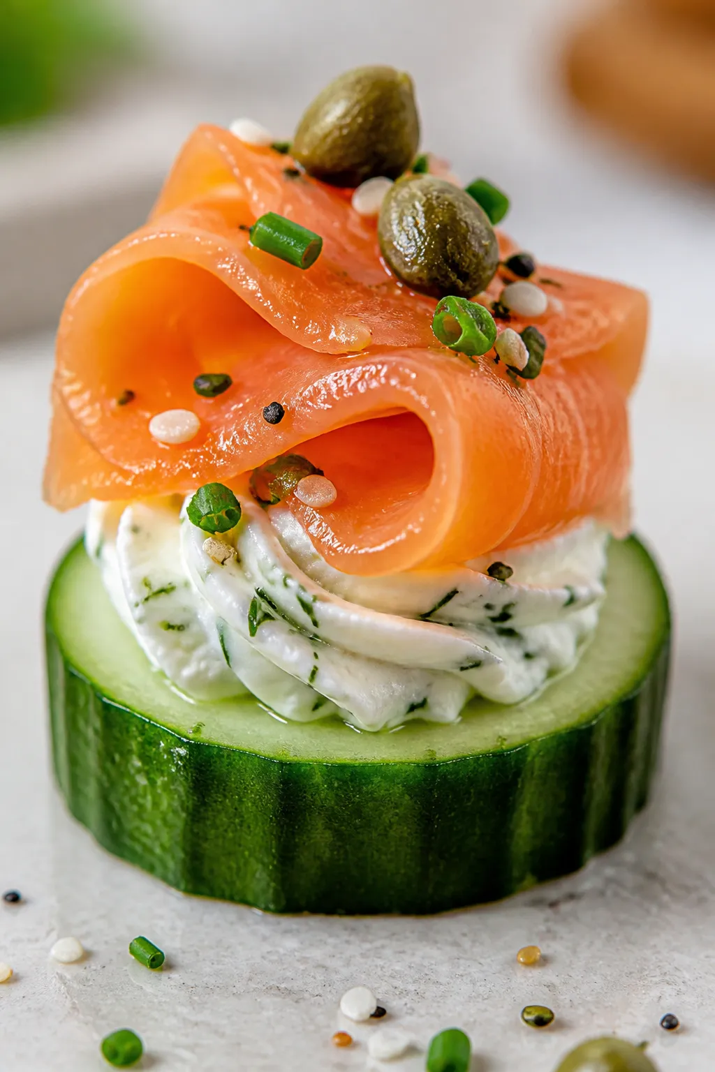 Close-up detail: A single assembled keto smoked salmon cucumber bite with a thick 1/2-inch cucumber