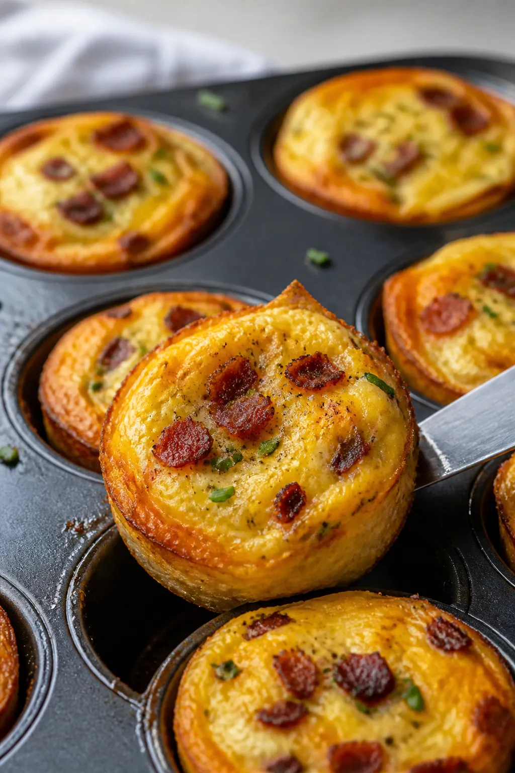 Close-up detail: Golden, just-baked keto egg muffins still in a well-greased muffin tin, centers bar