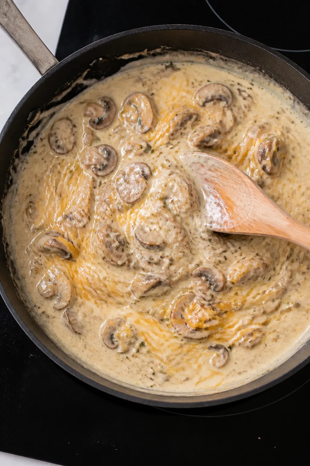 Cooking process shot: The creamy base coming together in a skillet—sautéed mushrooms and onions c