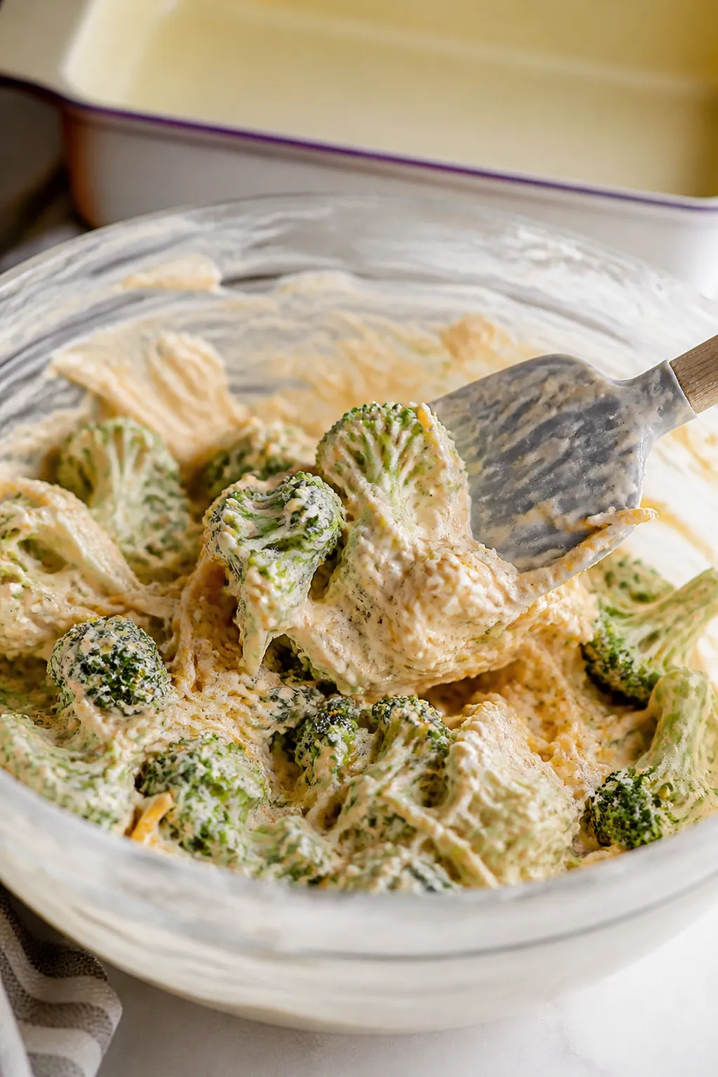 Cooking process: The coated broccoli being folded into the creamy base in a large mixing bowl—sauc