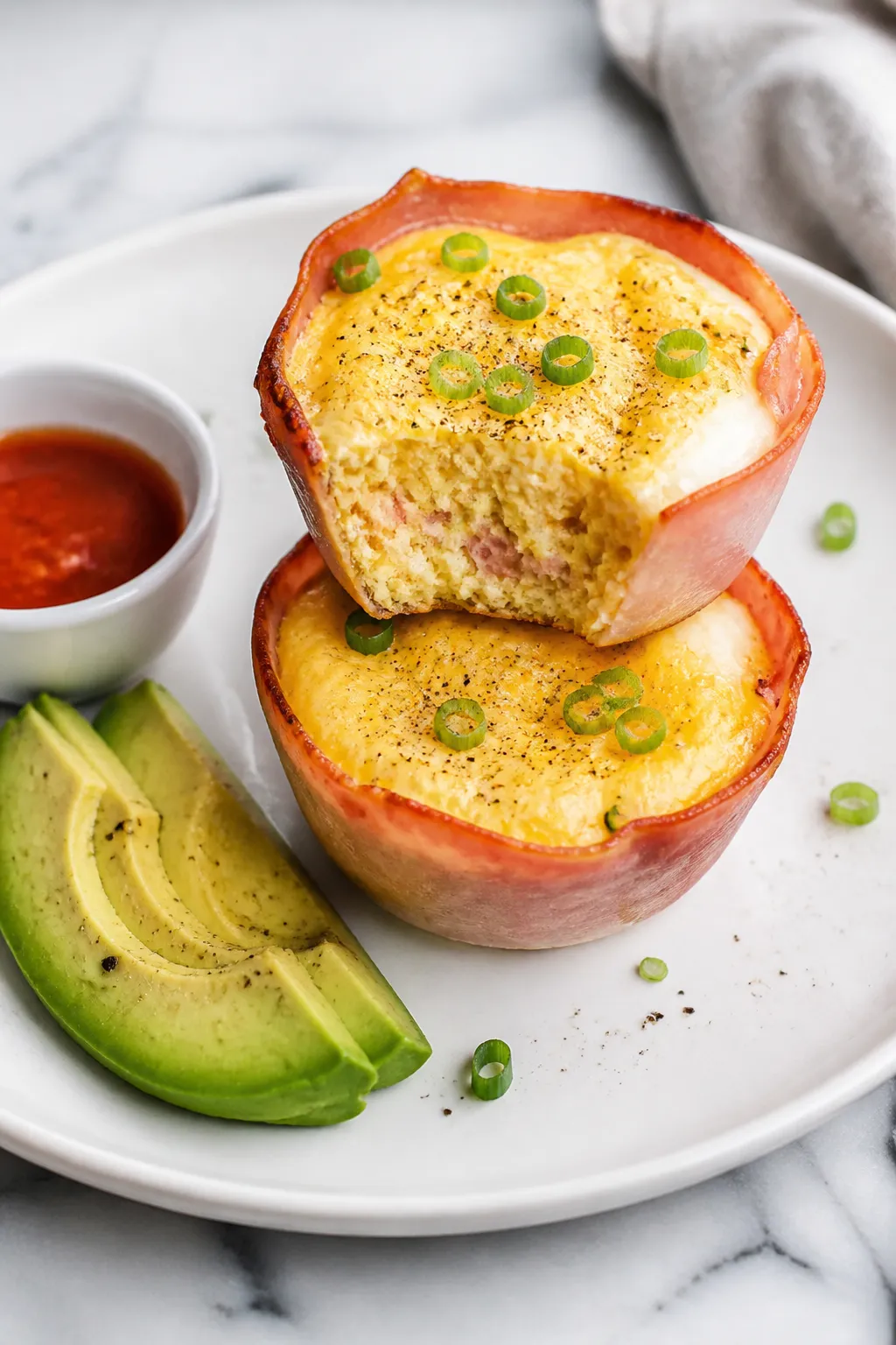 Final dish presentation: Beautifully plated keto ham and cheese egg cups on a matte white plate, two