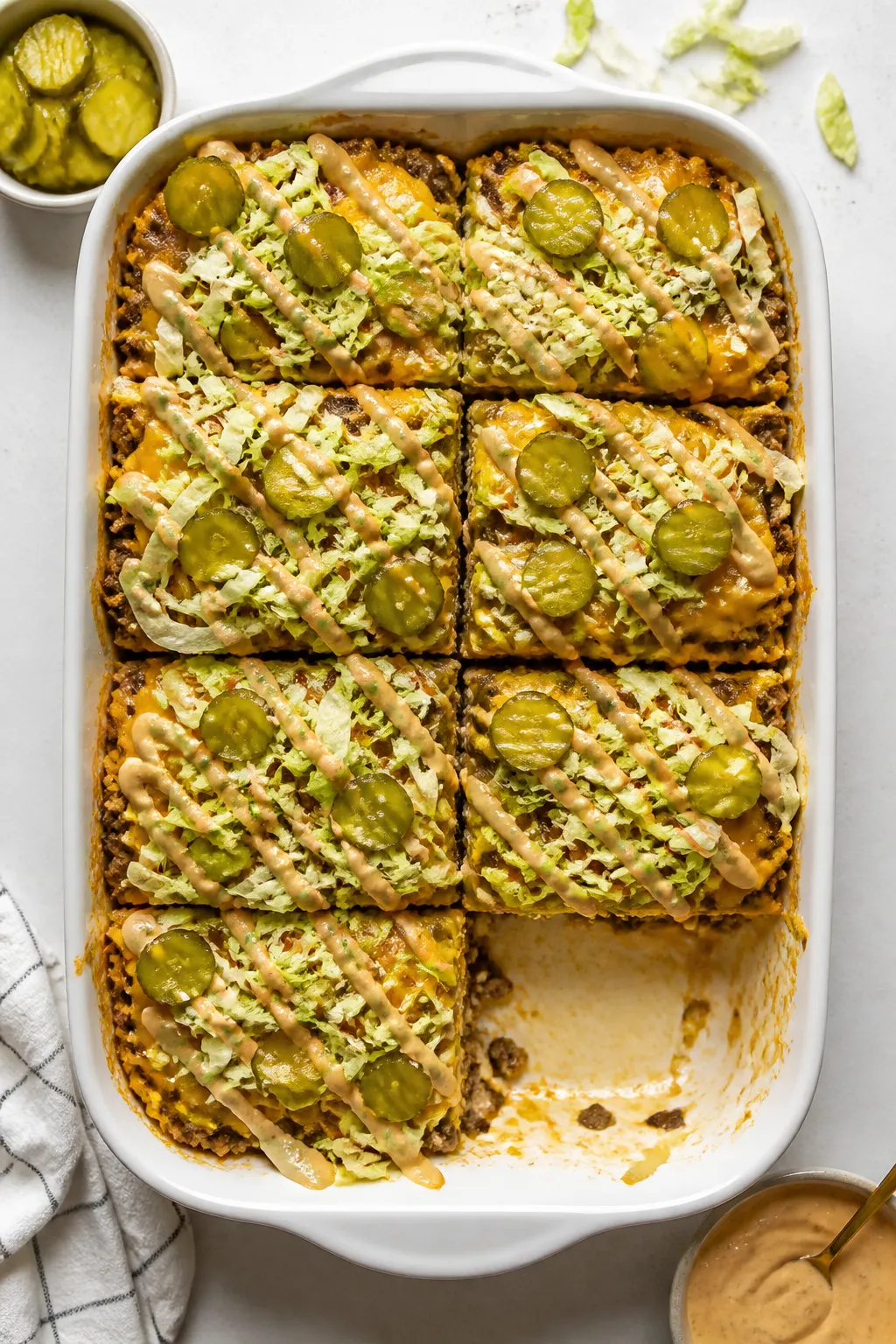 Overhead tasty top view: Fully dressed keto Big Mac casserole in a 9x13 dish, drizzled zig-zag with 